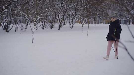 拿着登山杖在雪地里行走的老妇人