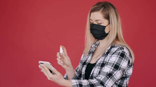 戴口罩的女人给手机消毒