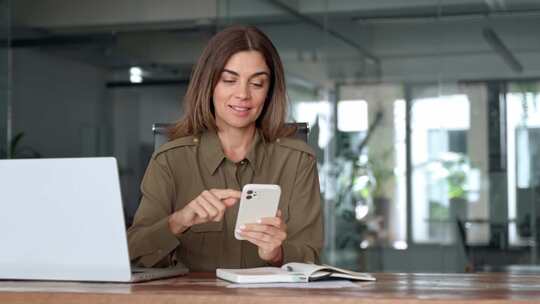 微笑成熟的商务女性高管使用手机在办公室工