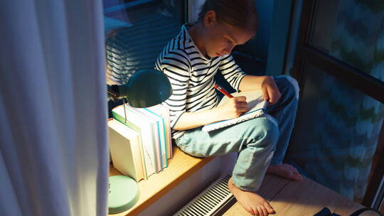夜晚女孩坐在窗台上写作业