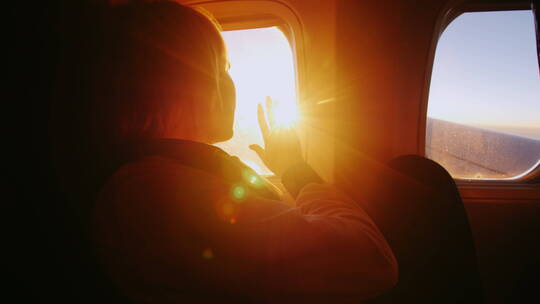 年轻女子从飞机窗户看太阳