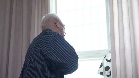 老人室内窗边站立远望