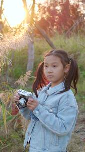 秋天在公园花丛中用照相机拍照的中国女孩