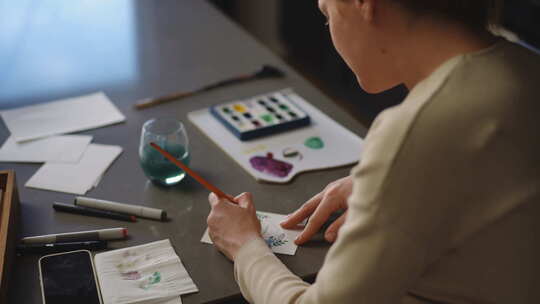 自制贺卡一个女人坐在桌旁用水彩画贺卡