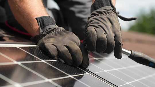 技术人员将太阳能电池板固定在屋顶上，以实现可持续的未来