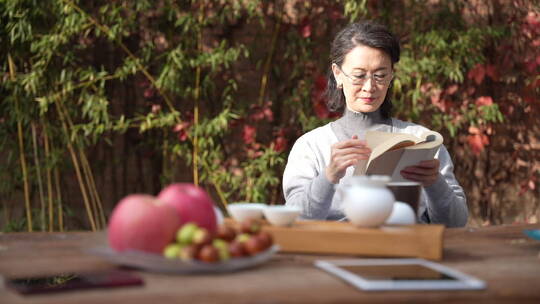 老年女人坐在院子里看书视频素材模板下载