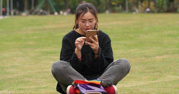 女大学生在草上上看手机浏览社交媒体