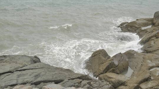 海边浪花拍打礁石，沙滩