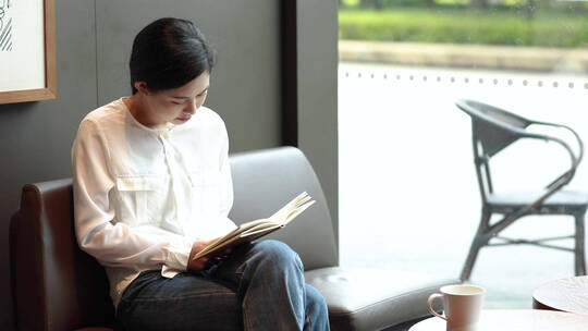 青年女性坐在咖啡馆看书