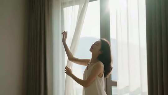 女子窗边拉开窗帘迎阳光