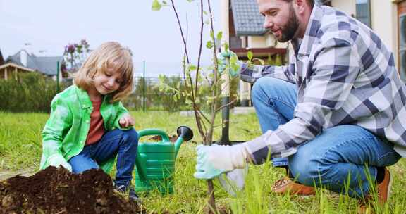 快乐快乐的高加索父亲和小儿子在果园种树并