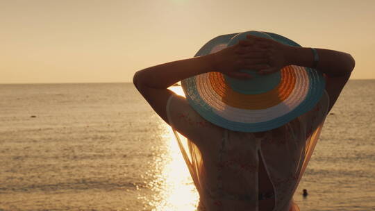 戴帽子的女人站在海边看日出
