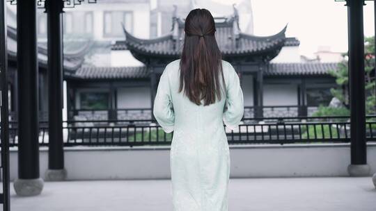 身穿汉服年轻女子走到中式合院景观池边