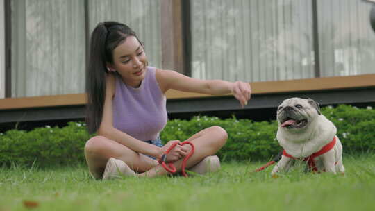 年轻女子和她的哈巴狗在花园草坪上休息