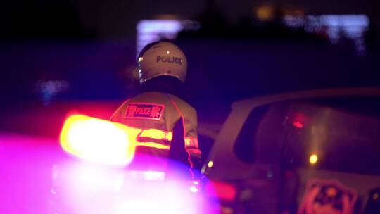 夜晚闪烁的警灯下交通警察在路口执勤