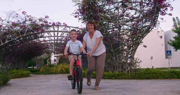 祖母正在和她的孙子骑自行车祖母正在教她的