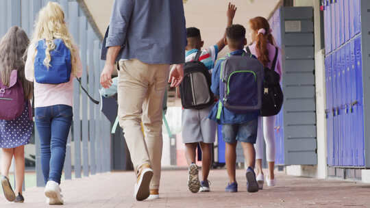 多样化的男老师和快乐的小学生在学校散步