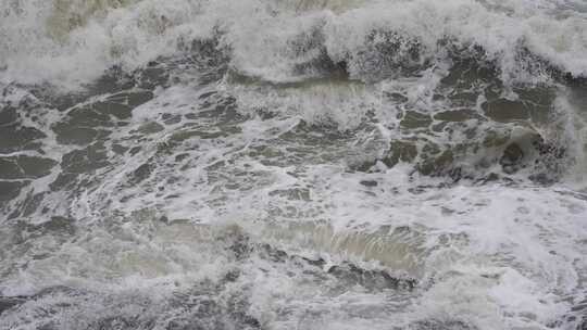 海浪拍打岩石浑浊海水冲刷礁石浪花阴天大海