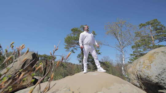 一个穿白衣的男人在山顶上唱歌一个穿白裤子
