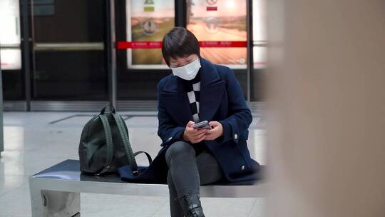 在地铁车站等车使用手机的亚洲女性