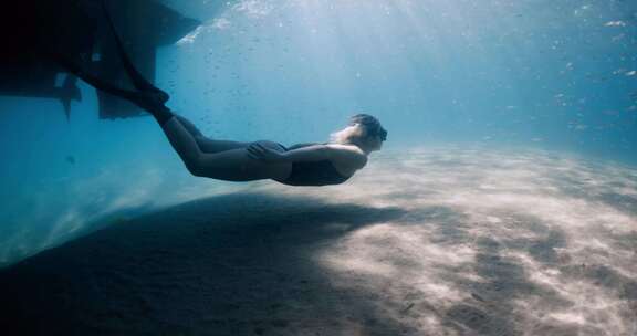 女子自由潜水员在蓝色大海水下游泳女子在码