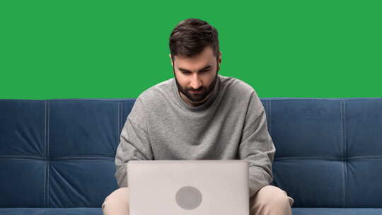 男人远程工作笔记本电脑聊天浏览互联网沙发隔离绿屏色度键视频素材模板下载