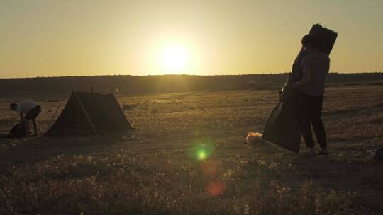 夕阳下搭帐篷的夫妇