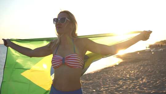 海滩上穿着泳衣的美丽年轻女子，挂着巴西国旗。
