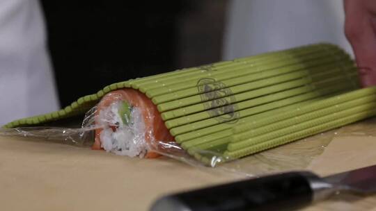 厨师的手卷寿司卷。寿司制作过程。卷寿司卷