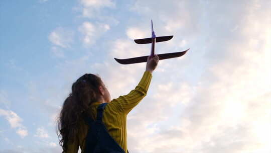 日落夏日大自然中快乐的小女孩带着玩具飞机