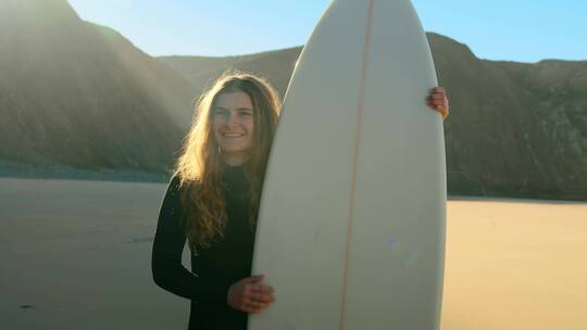 女孩拿着冲浪板站在沙滩上微笑