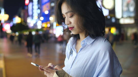 夜晚城市街头年轻白领看手机发消息