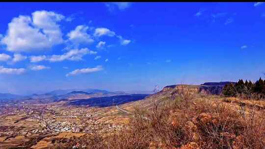 蓝天白云下的开阔山地乡村景色