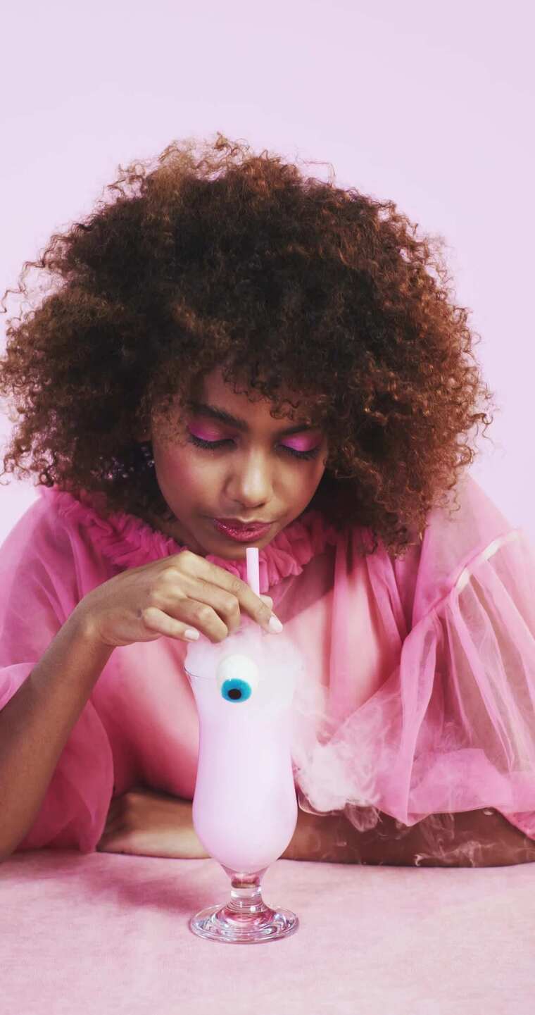 令人毛骨悚然的年轻女人喝着吸烟鸡尾酒