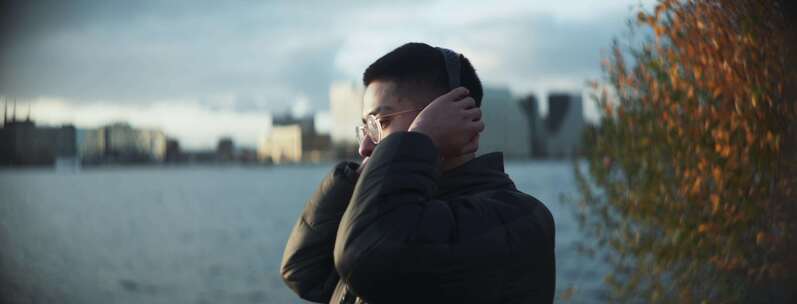 戴耳机的男人在河边随着节奏摇摆