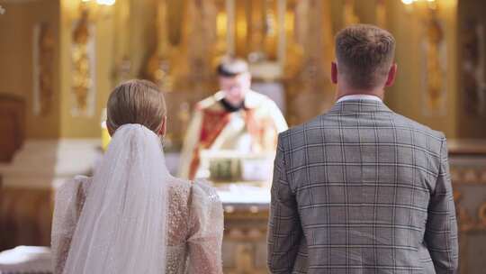 新娘和新郎在婚礼上背靠背站在天主教堂里