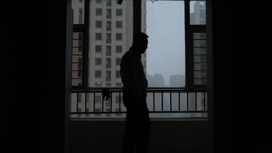 在窗前徘徊踱步思考问题的男人剪影