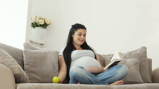 孕妇坐在沙发上和两个女儿玩耍