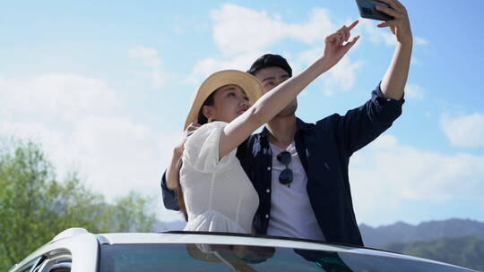 青年夫妻在汽车上用手机拍照
