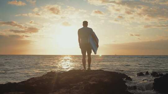 男人站在日落礁石上