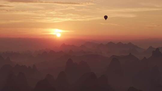 日出时分热气球飞于山峦之上