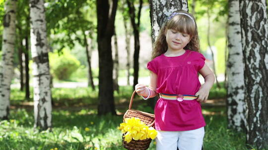 带着一篮子郁金香的女孩站在树林里