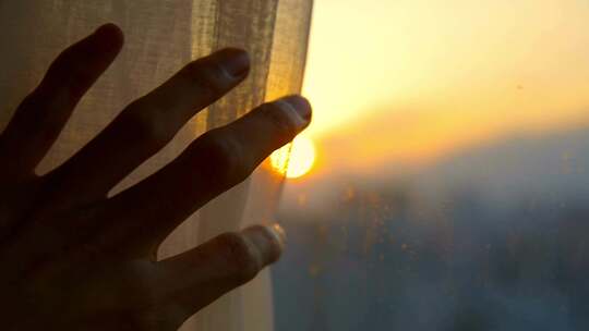 早上手拨开窗帘露出日出