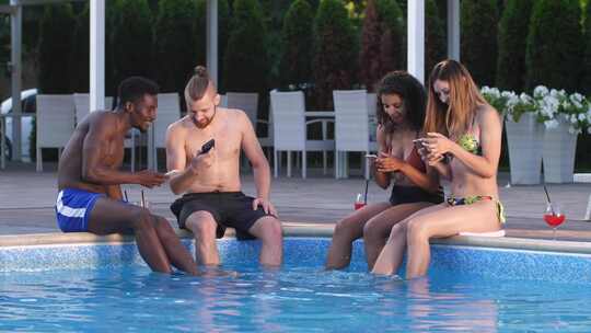 一群人坐在游泳池边使用手机