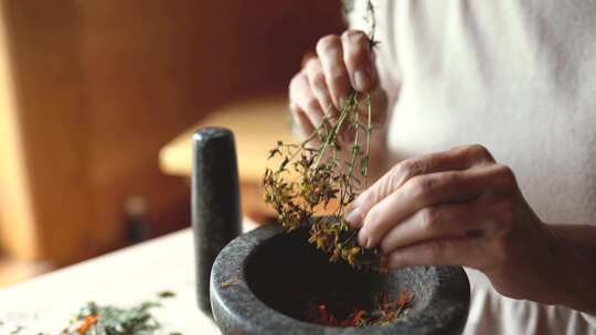 一个把干花放在砂浆和杵里的人