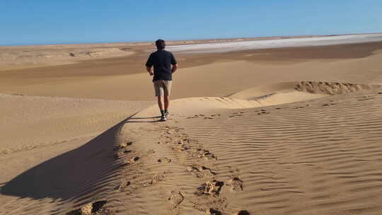 一个人走在撒哈拉沙漠上，留下脚印。