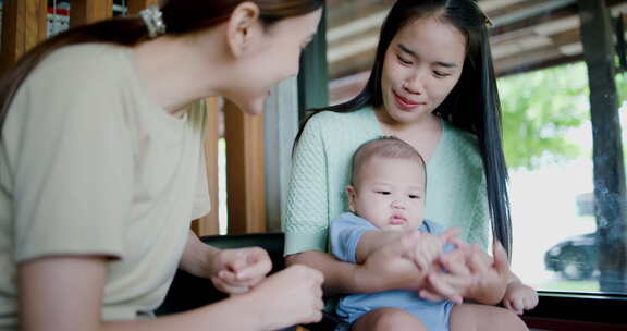 两个年轻的亚洲女人在咖啡馆里开心地和一个