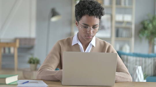 年轻非洲女孩在笔记本电脑上工作