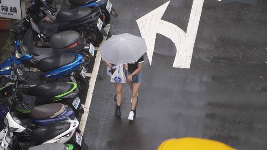 撑着雨伞走在雨下的两个女孩