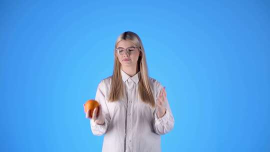 年轻的金发白人戴眼镜聪明的女士玩橙色水果